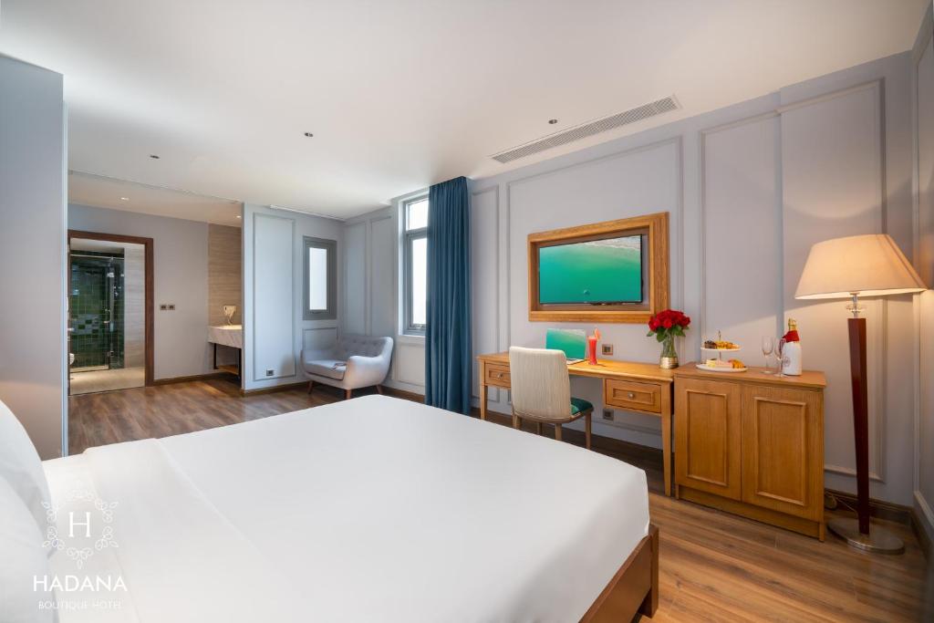 A king room photographed from the bed, showing the desk, television, window and entry area.