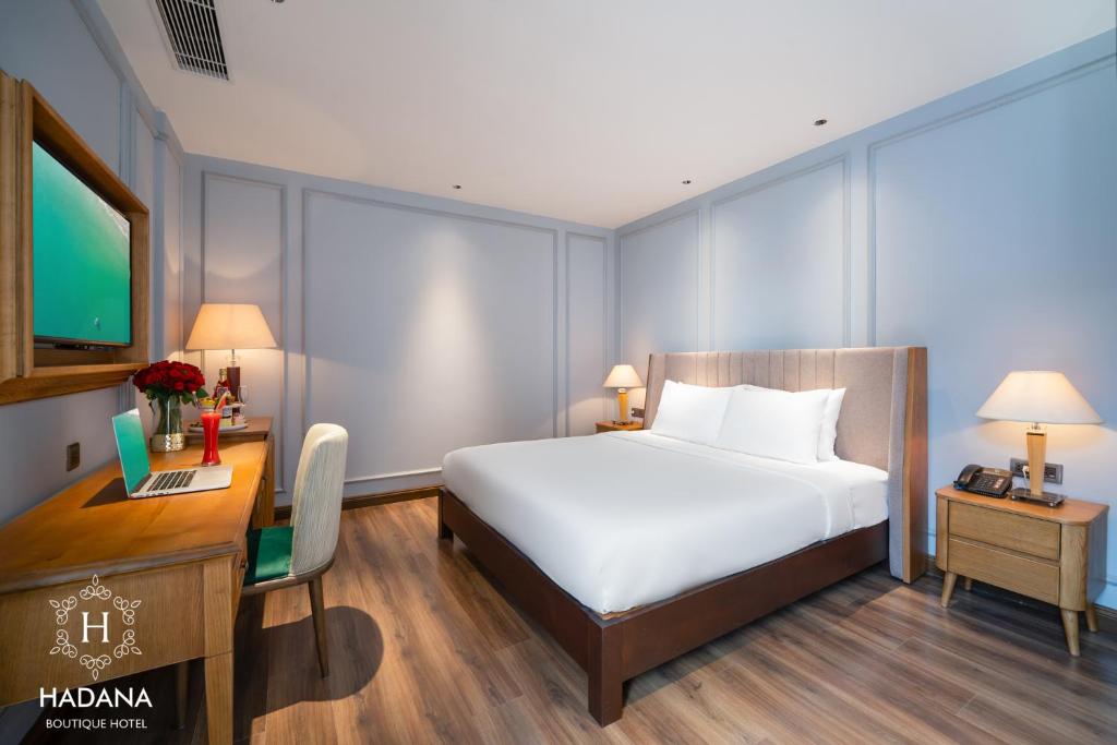 A polished king room with a desk, television, bedside tables and a full-length bed view.