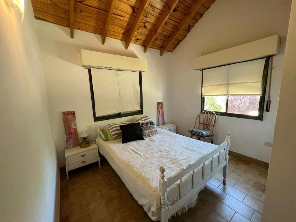 1 Schlafzimmer mit einem weißen Bett und 2 Fenstern in der Unterkunft Casa en el Balneario El Cóndor, muy cerquita del mar. in Viedma