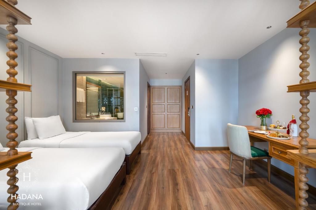 A twin room with two single beds, a desk and a glass-fronted bathroom view.