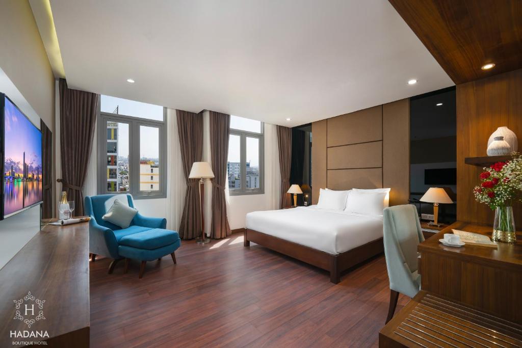 a hotel room with a bed and a blue chair at Hadana Boutique Hotel Danang in Danang