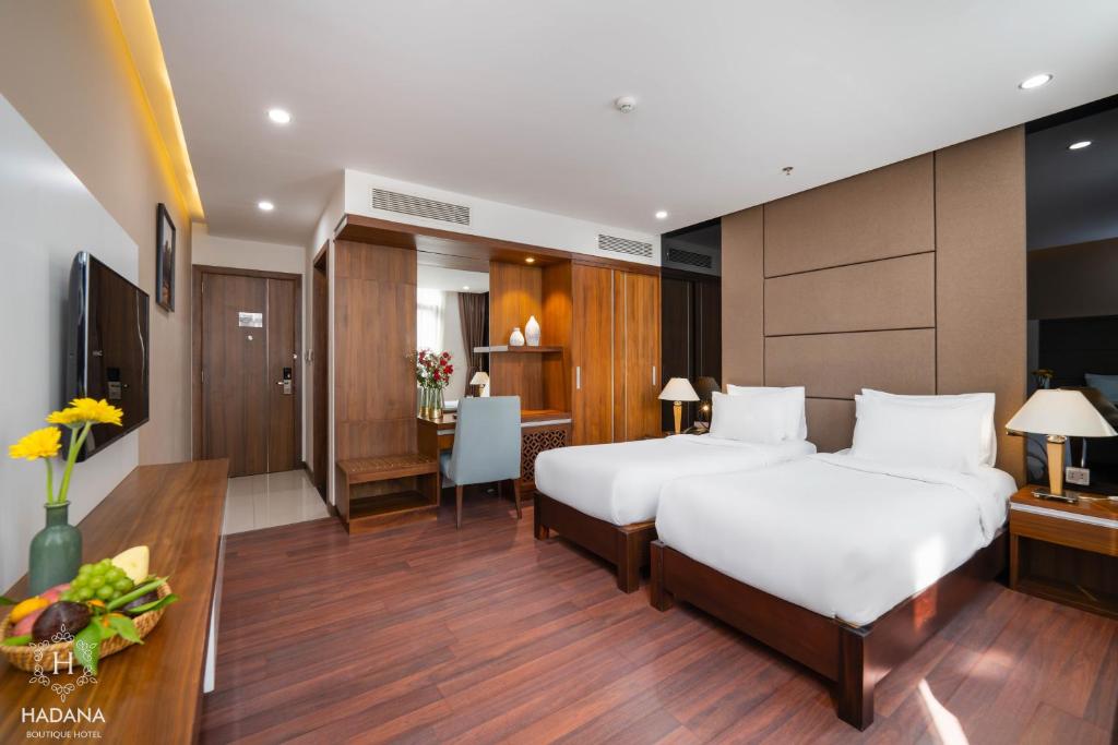 A twin room with a compact desk, generous built-in storage and a wall-mounted television.