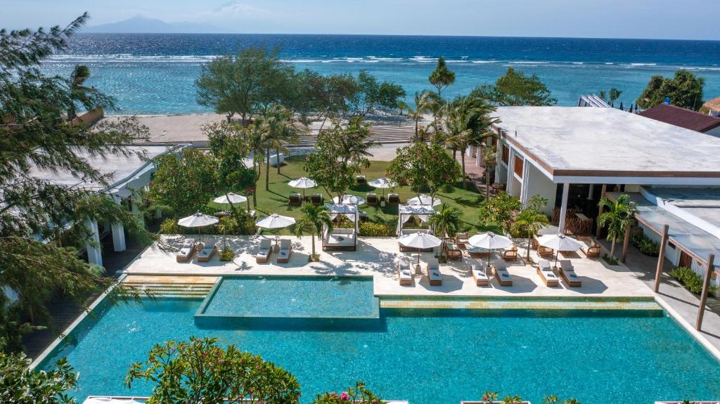 an aerial view of a resort pool with chairs and umbrellas at Cocana Resort Gili Trawangan in Gili Trawangan