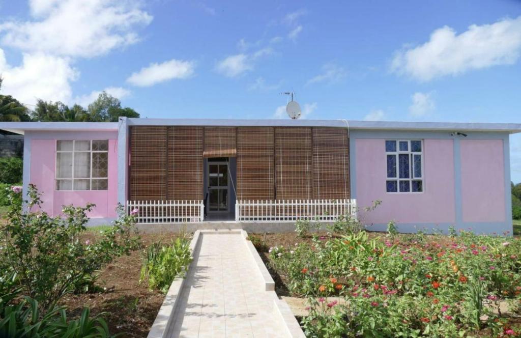 ein rosa und weißes Haus mit einem Garten in der Unterkunft Bois Gournable in Rodrigues Island