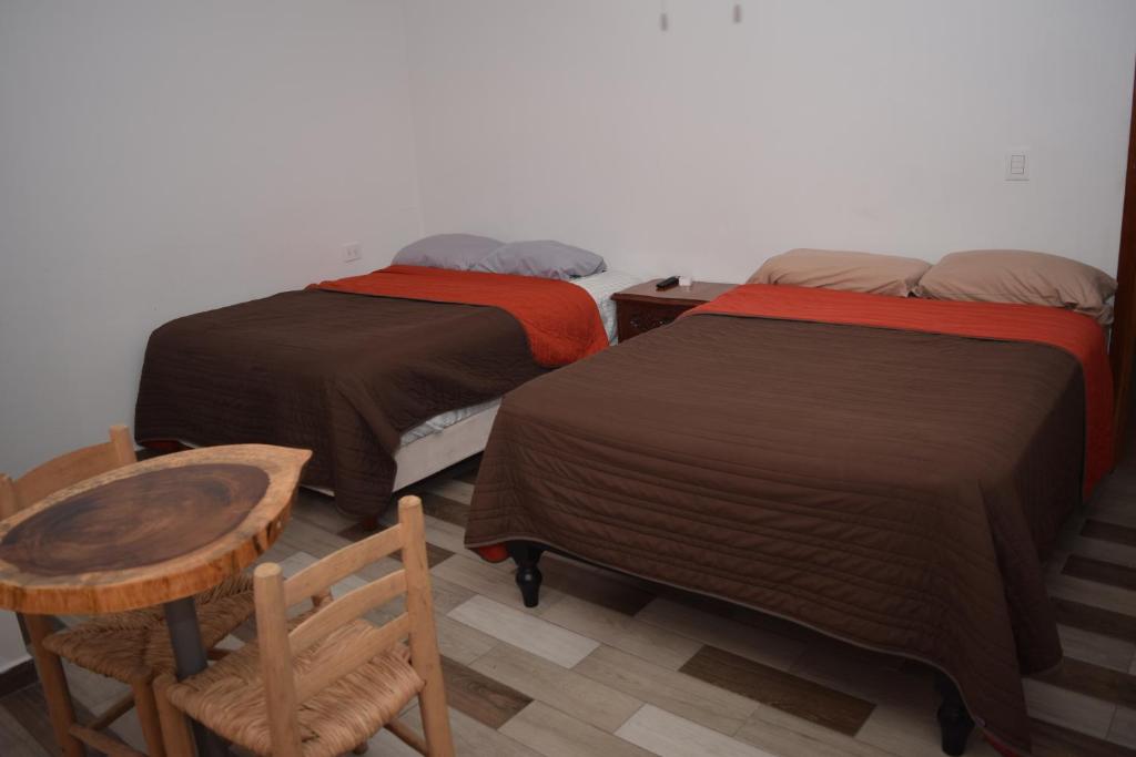 two beds in a room with a table and a chair at Estancia Vacacional 20 Aguas in Ursulo Galván
