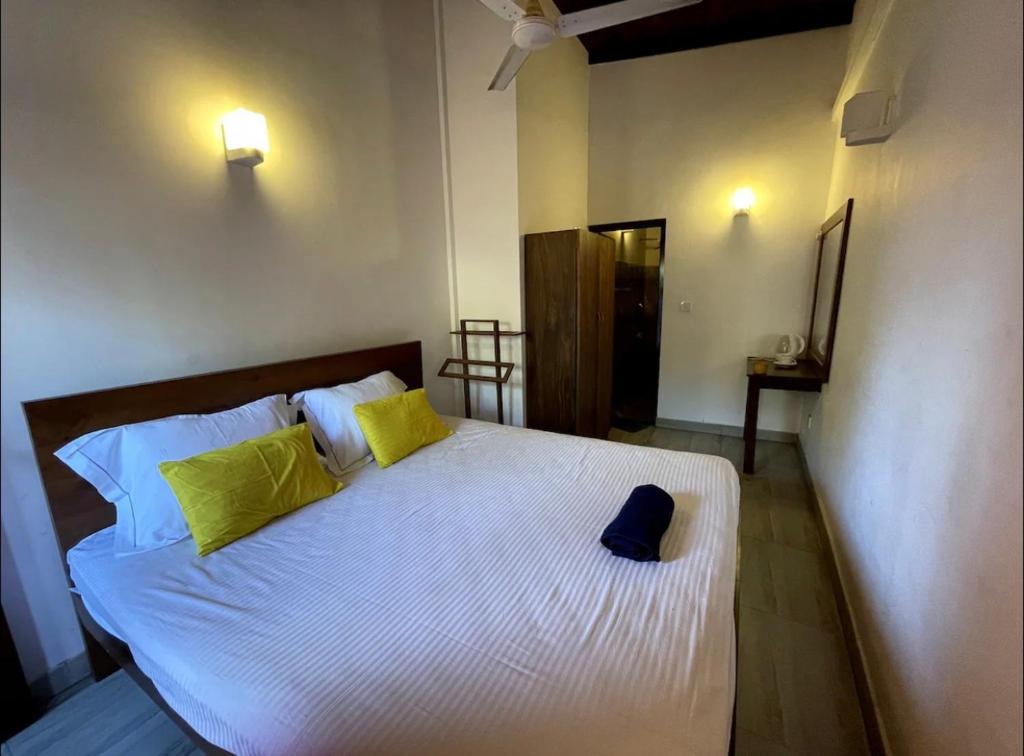 a bedroom with a large white bed with yellow pillows at mandodari in Negombo