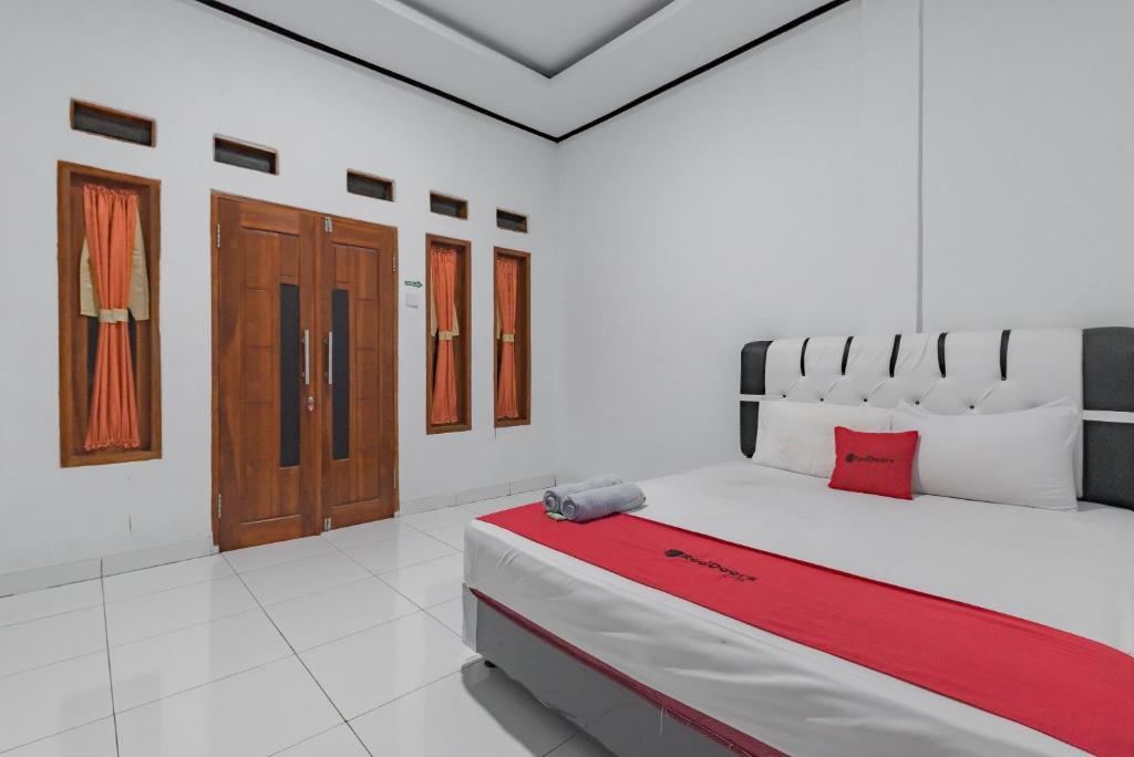 a white room with a large bed with a red blanket at RedDoorz @ Geopark Ciletuh Sukabumi in Cilowa