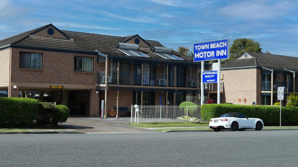 mały biały samochód zaparkowany przed budynkiem w obiekcie Town Beach Motor Inn Port Macquarie w mieście Port Macquarie