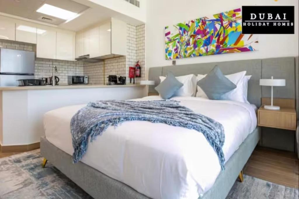 a bedroom with a large bed and a kitchen at 151 Residence Jumeirah Gardens in Dubai