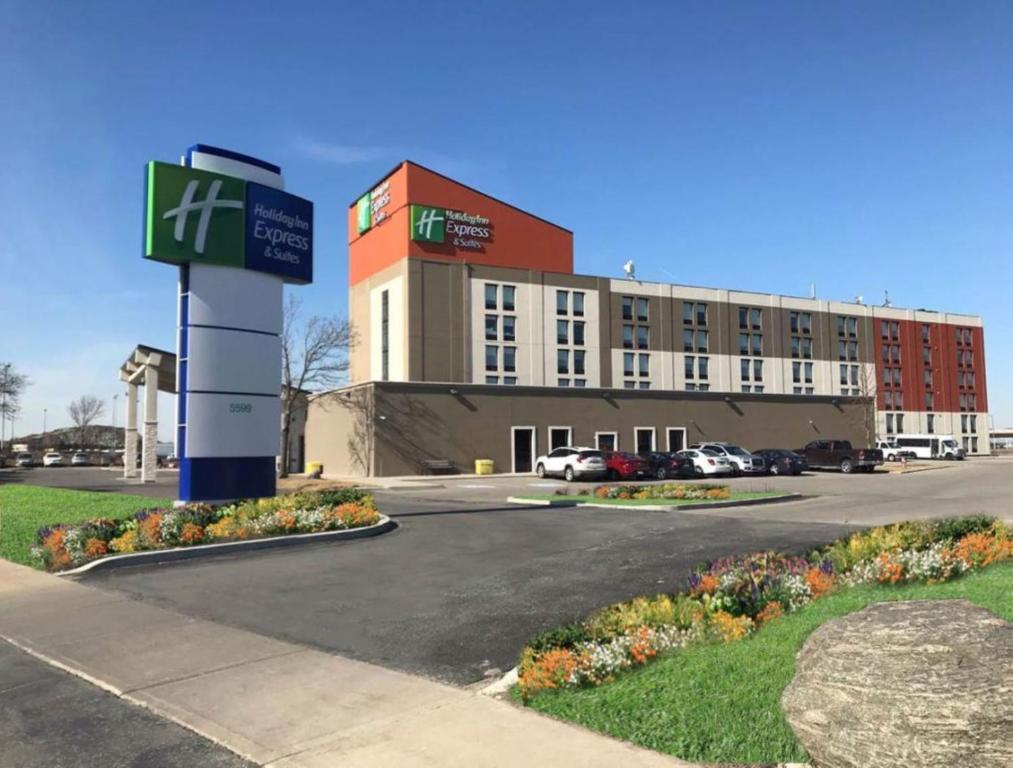 a building with a sign in front of a parking lot at Holiday Inn Express & Suites Toronto Airport West, an IHG Hotel in Mississauga