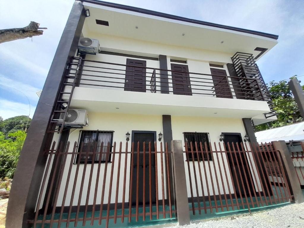 a white house with black doors and a fence at Palawan-Residence B&B in Puerto Princesa City