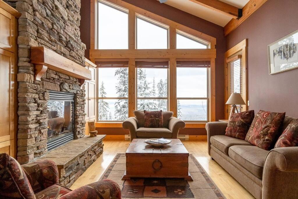una sala de estar con una gran chimenea de piedra. en Eagle Ridge Pet-Friendly Chalet, en Big White