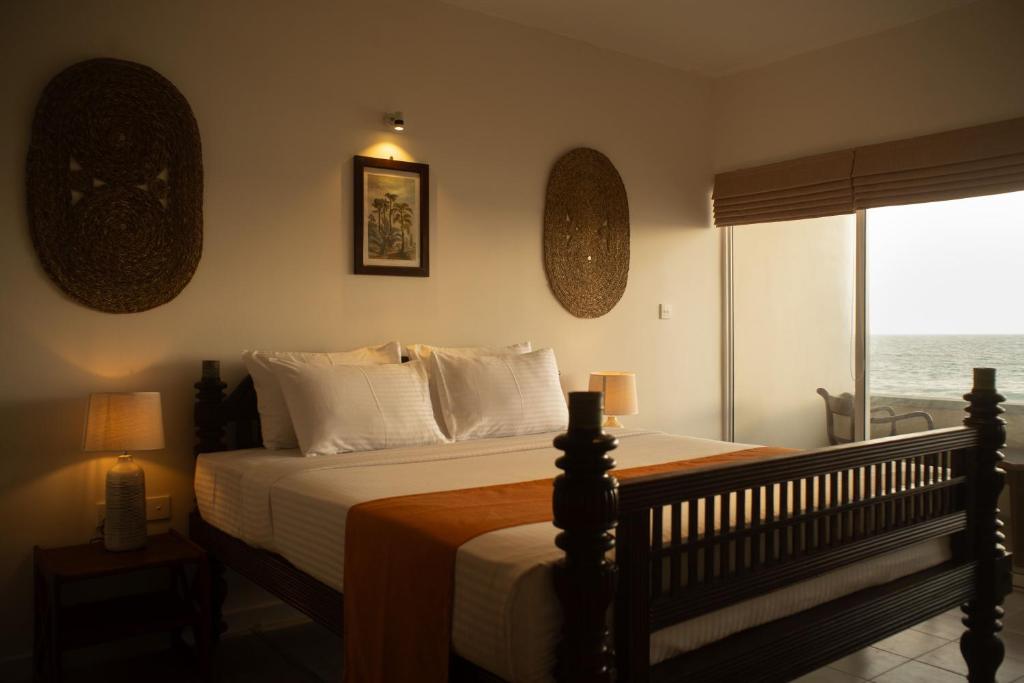 a bedroom with a bed with a view of the ocean at Neevana Hotel Hikkaduwa in Hikkaduwa