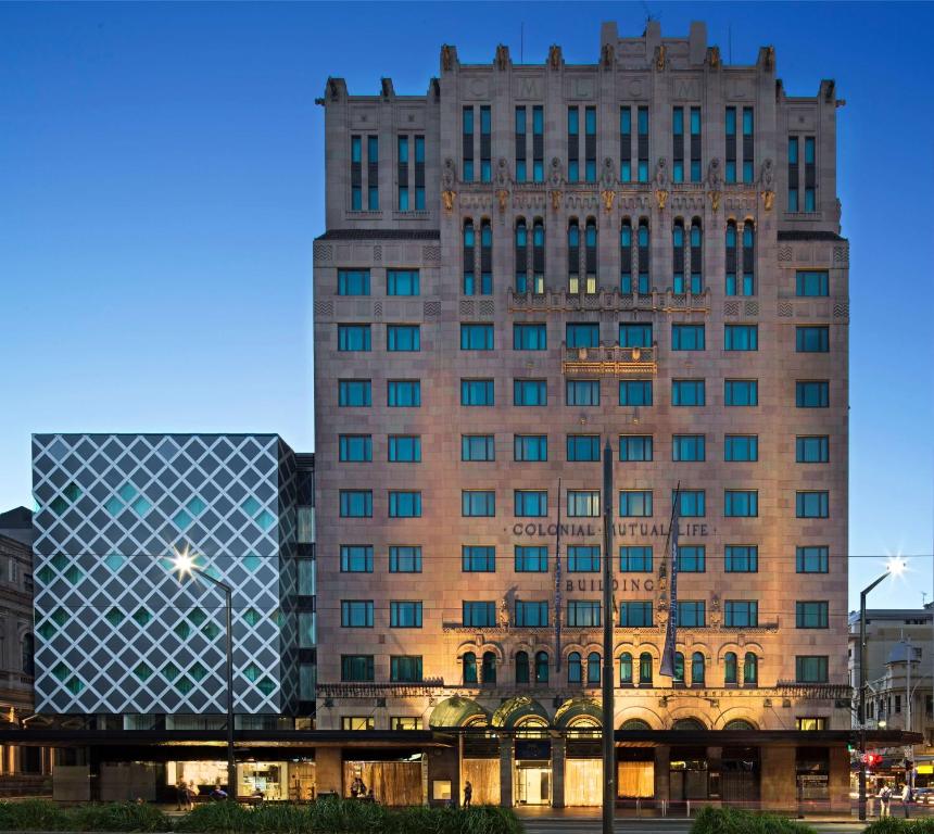 um edifício alto com uma fachada de vidro numa cidade em Mayfair Hotel em Adelaide