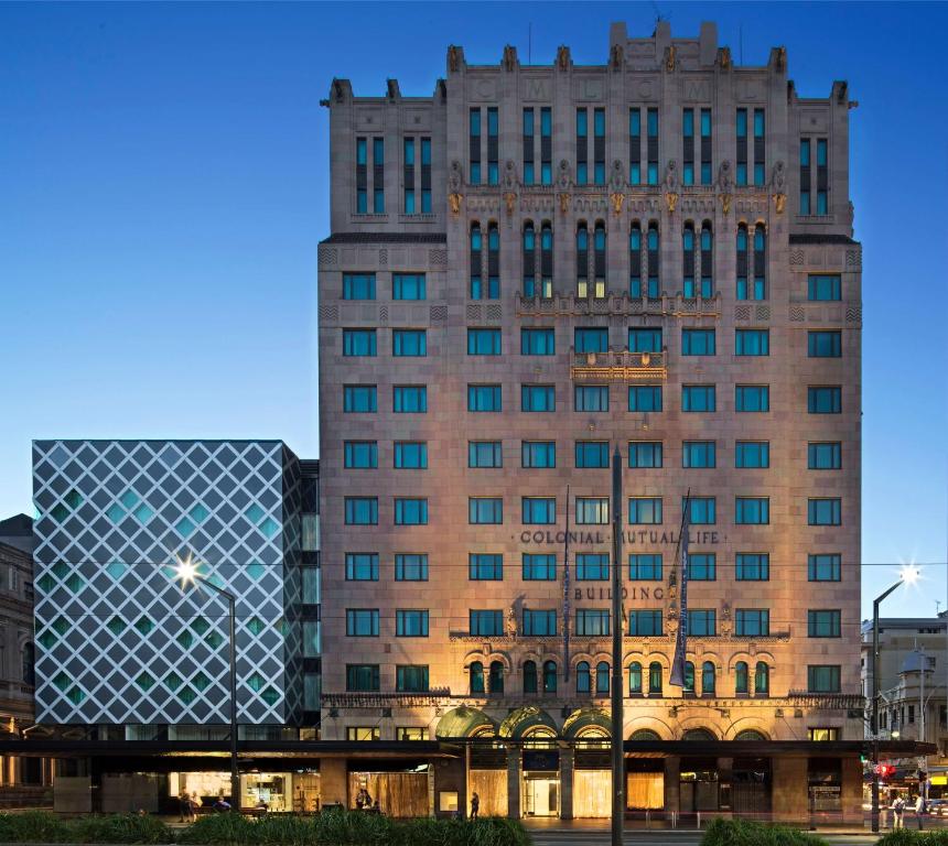 a tall building with a glass facade in a city at Mayfair Hotel in Adelaide