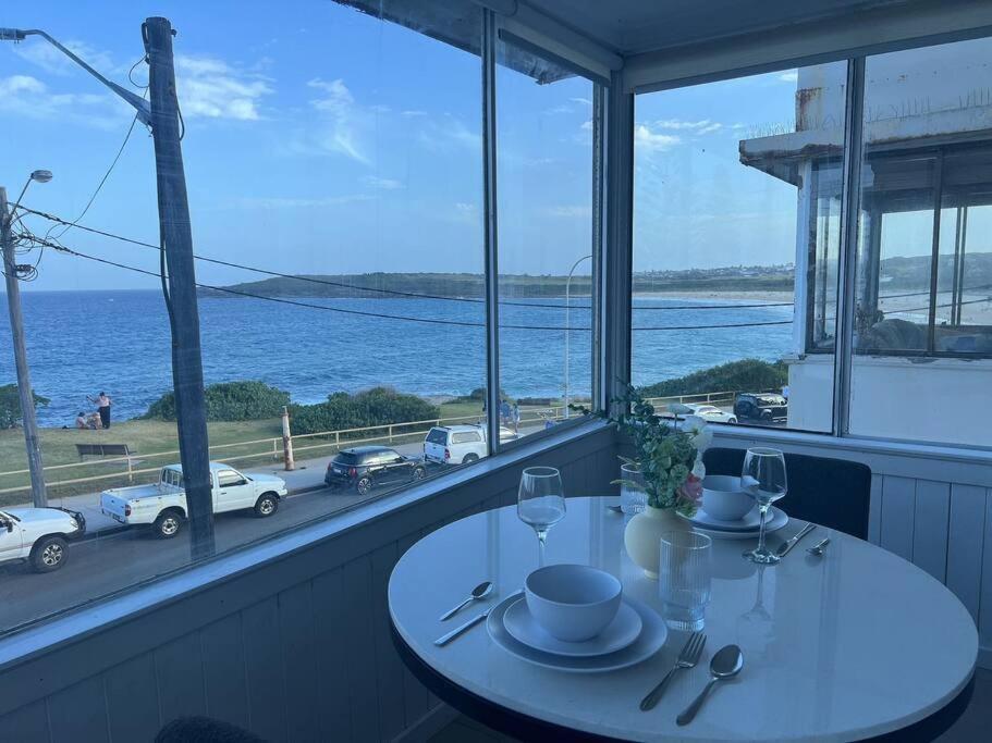 a table with wine glasses and a view of the ocean at Ocean View 1 bedroom Private Apartment Near Maroubra Beach in Sydney