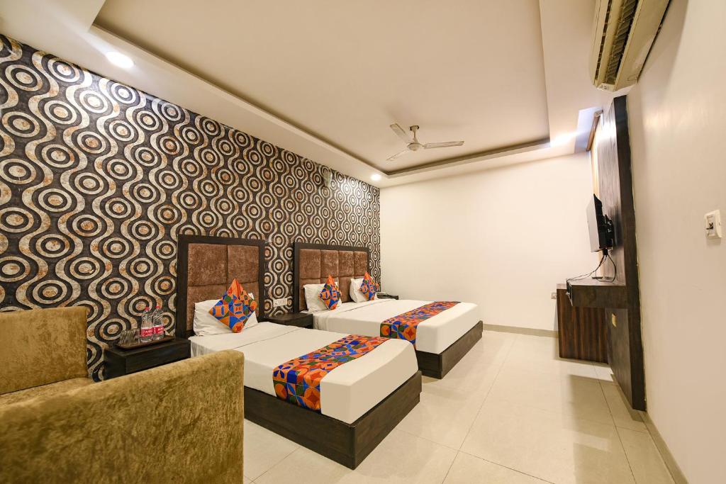 Cette chambre comprend 2 lits et une télévision. dans l'établissement FabHotel Belwood, à New Delhi