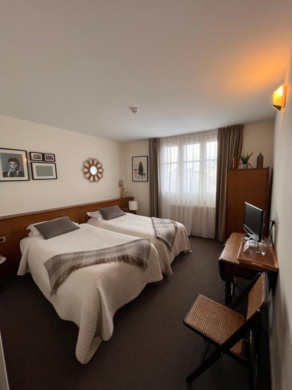 a hotel room with two beds and a desk with a laptop at Le Téméraire Hôtel in Charolles