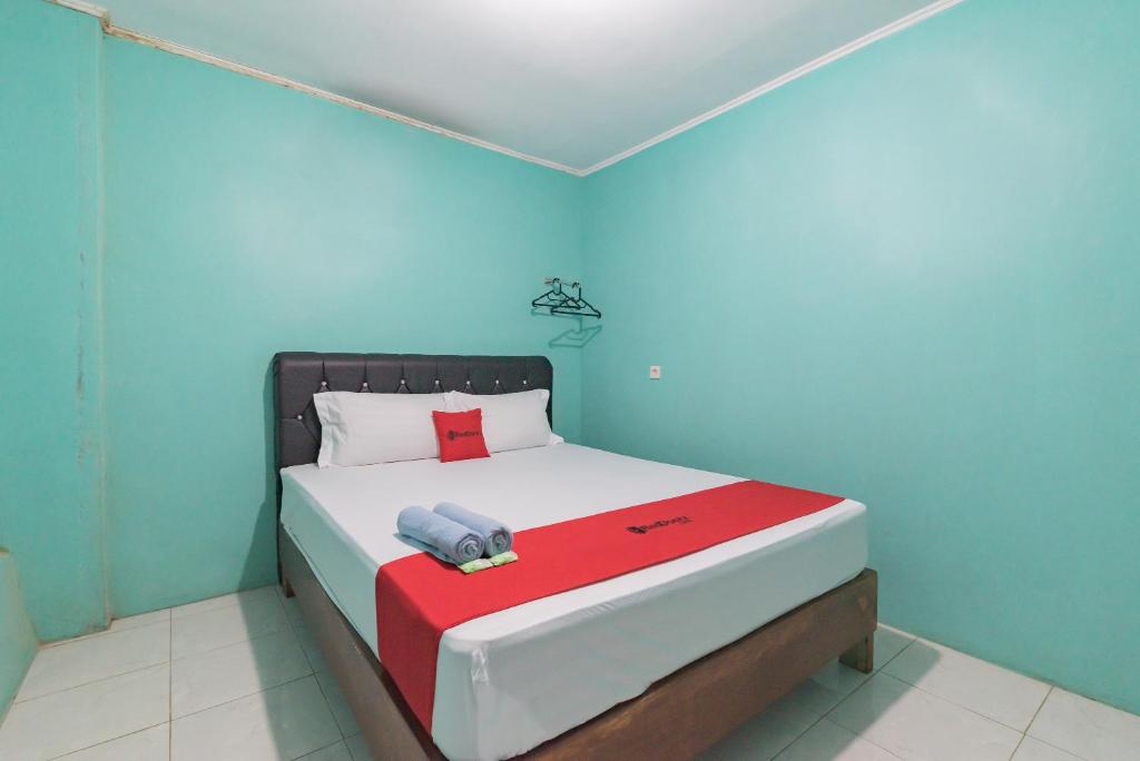 1 dormitorio con 1 cama con pared roja y azul en RedDoorz near Pantai Ujung Genteng, en Cijaringao