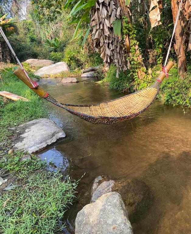 a hammock hanging over a stream of water at วิวดี ป่าเหมี้ยง โฮมสเตย์ in Ban Pa Miang