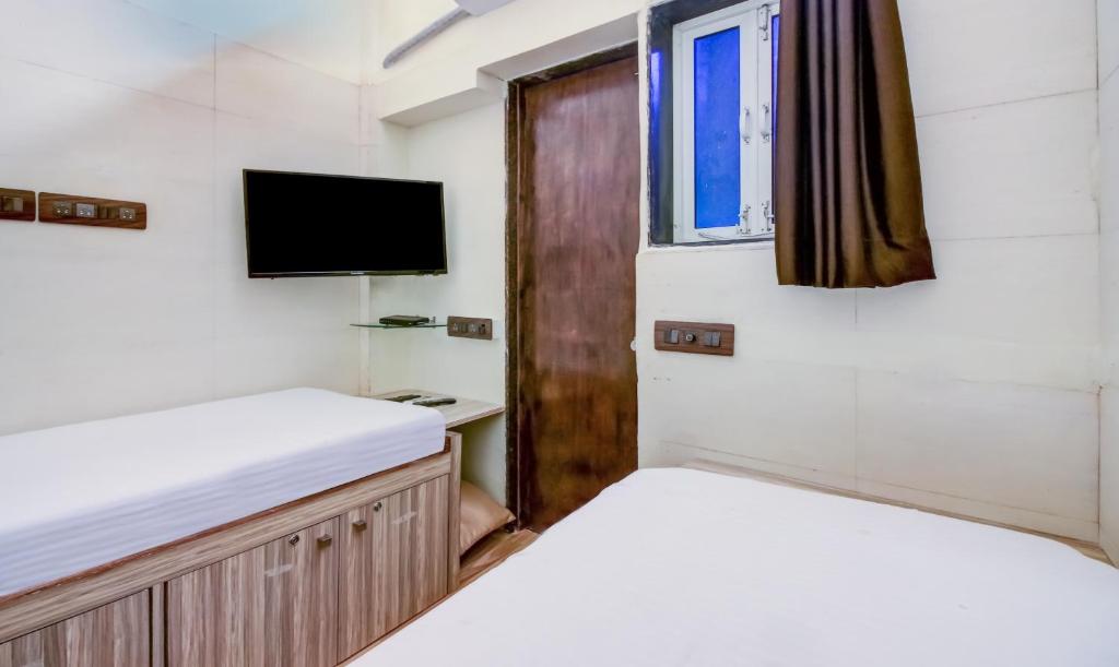 a bedroom with two beds and a tv at ZEST STAYS - MEADOW INN 1058 in Mumbai