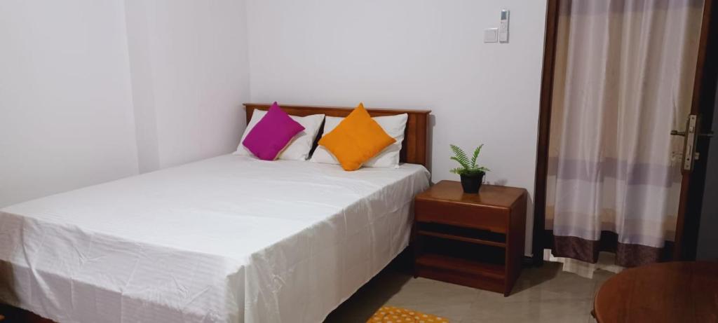 高爾的住宿－One bedroom upstair villa rent, near the Pinnaduwa interchange，卧室配有白色的床和色彩缤纷的枕头