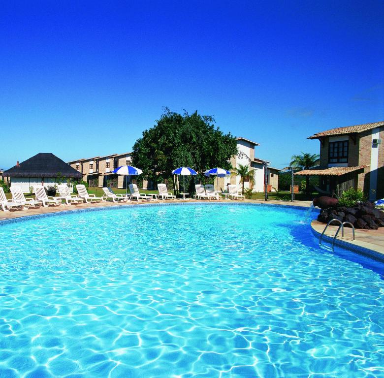 a swimming pool at a hotel with chairs and umbrellas at Hotel Varandas Mar De Pipa in Pipa