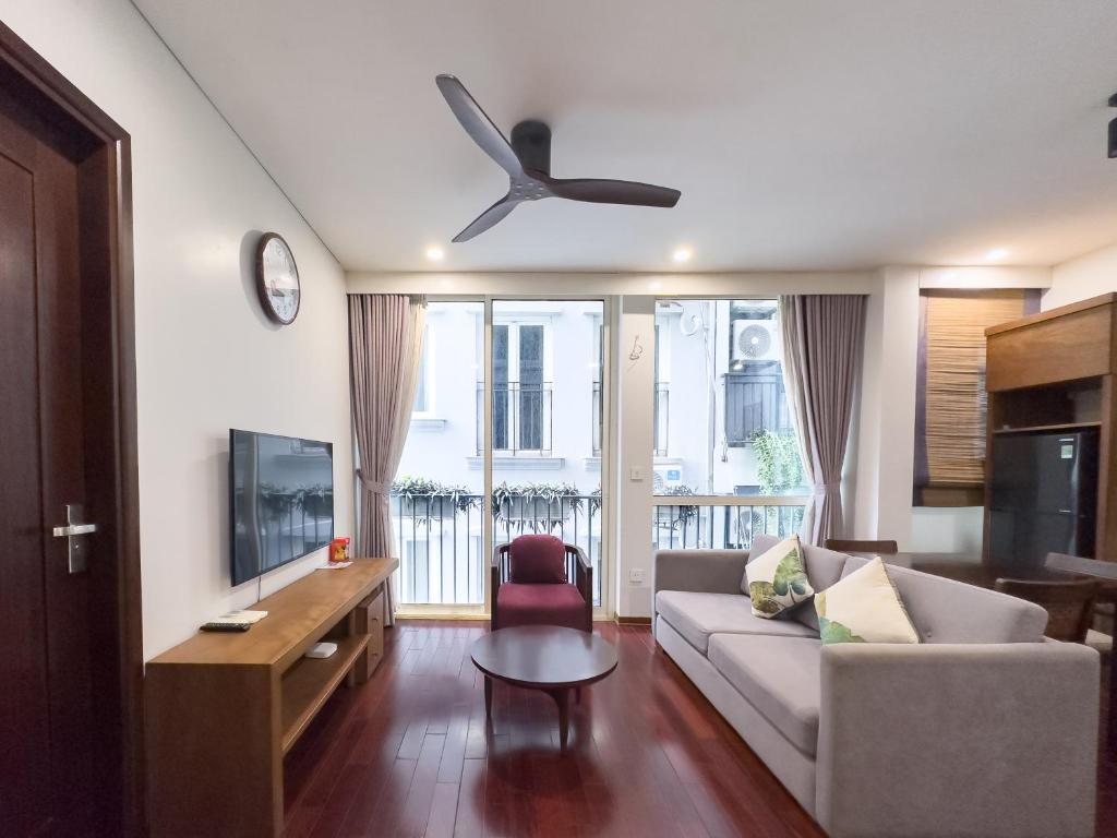 uma sala de estar com um sofá e uma ventoinha de tecto em Nikomix - SAKAMOTO II Apartment - 2 Bedroom 60m2 em Hanói