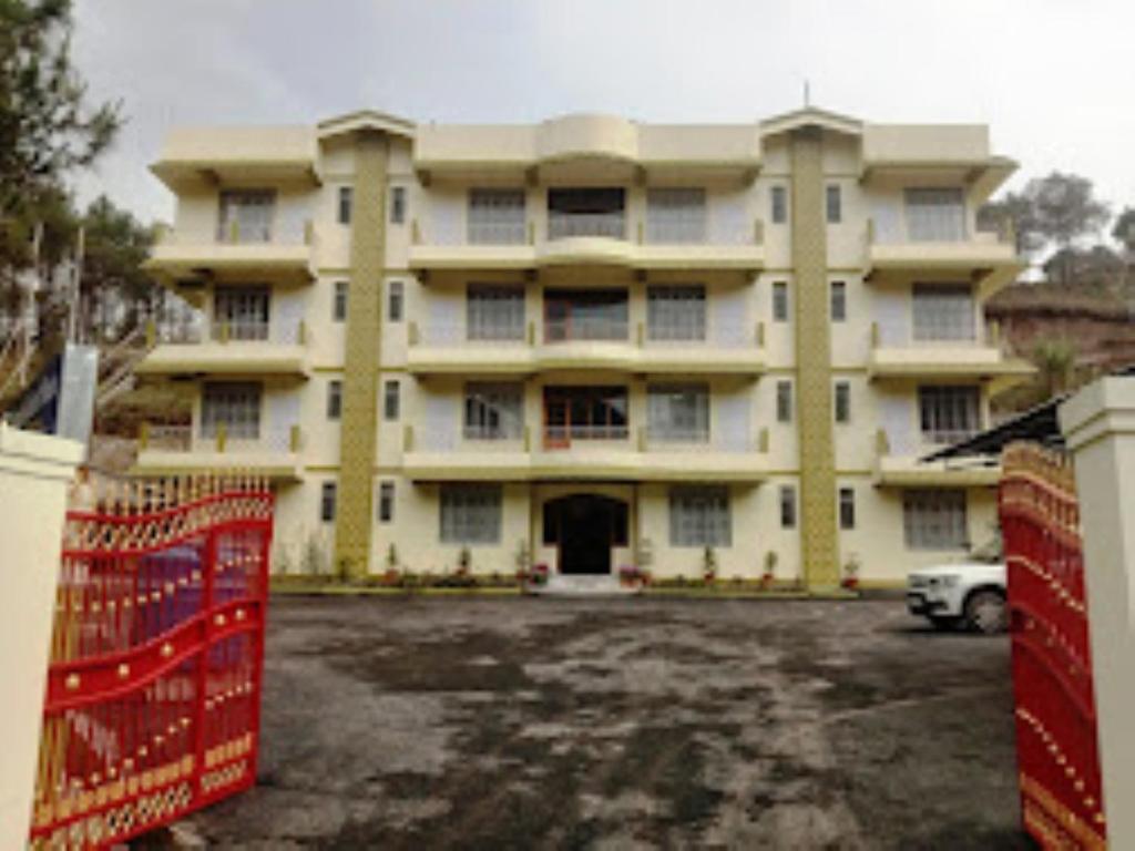 um grande edifício com um parque de estacionamento em frente em DAMEKI GUEST HOUSE , Shillong em Shillong