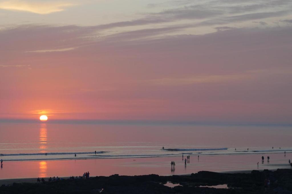 einen Sonnenuntergang am Strand mit Leuten am Strand in der Unterkunft 47 The Rest in Porthcawl