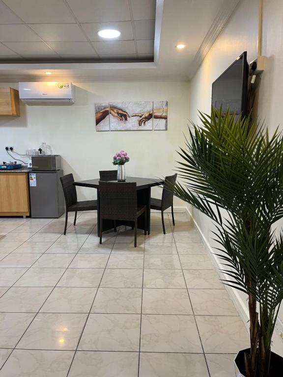 a dining room with a table and chairs and a plant at Mikocheni smart apartment in Dar es Salaam