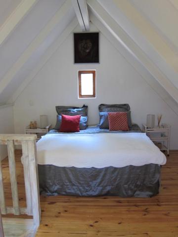 1 dormitorio con 1 cama con reloj en la pared en Vennebos cottages, en Knysna
