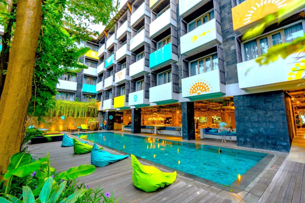 a hotel with a swimming pool in front of a building at IKOSHAROLD Suites Seminyak in Seminyak