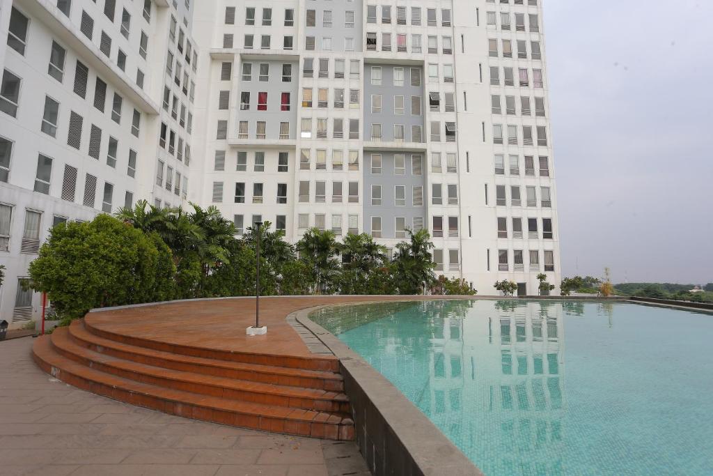 a swimming pool in front of a tall building at Capital O 93490 Yubi Room Patraland in Bekasi