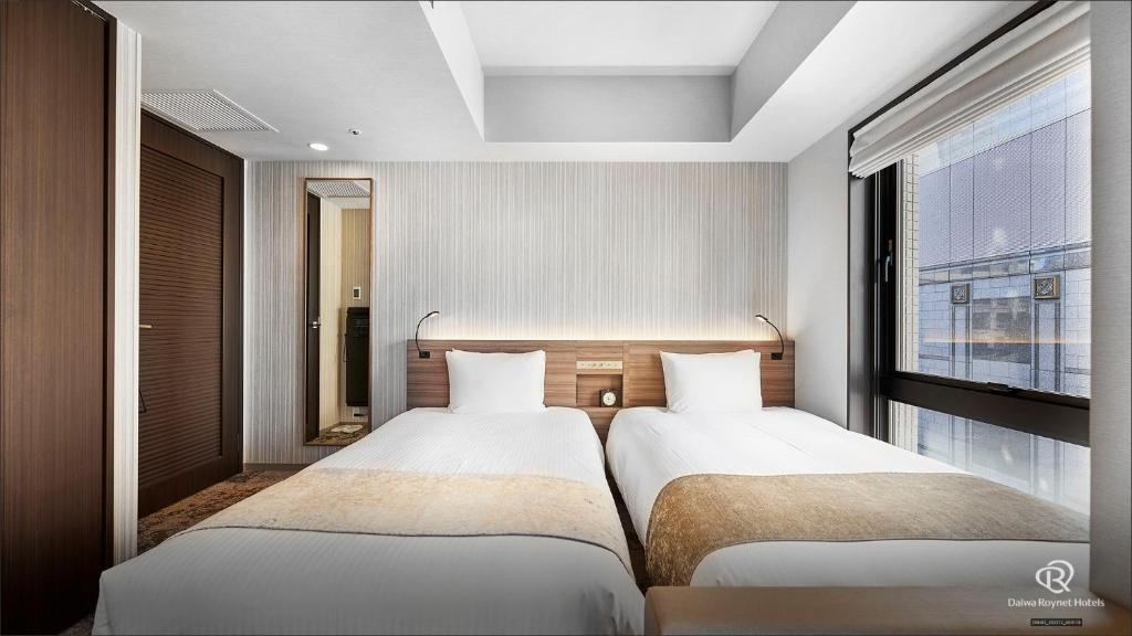 2 camas en una habitación con ventana en Daiwa Roynet Hotel Shimbashi, en Tokio