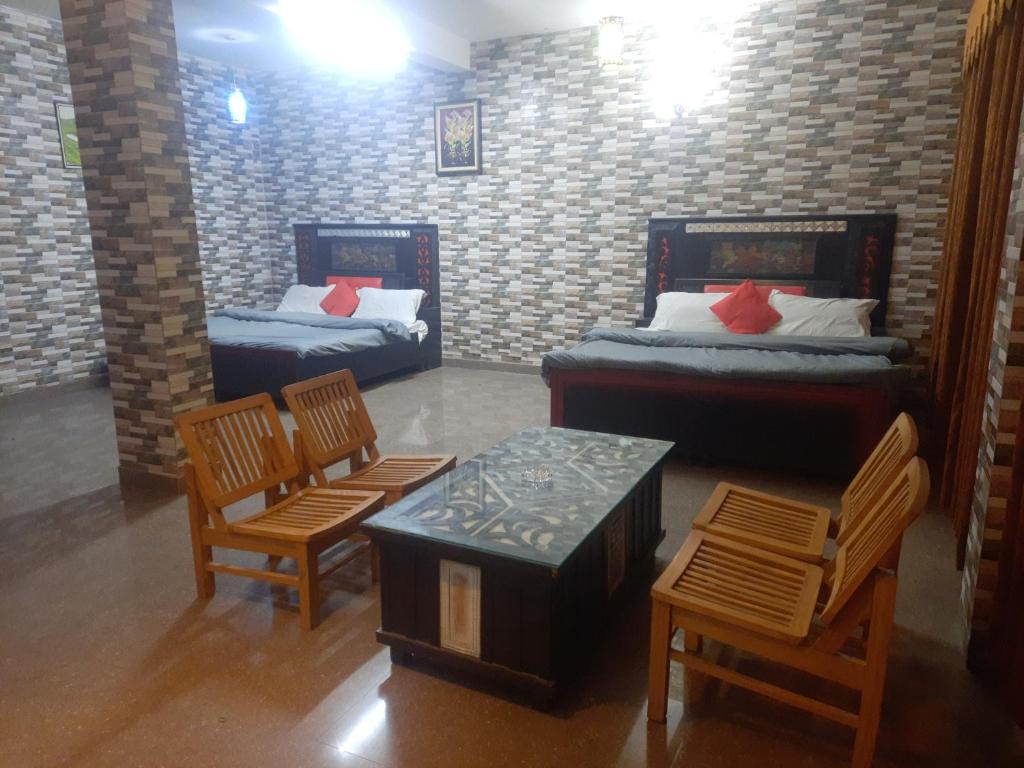 Habitación con 2 camas, mesa y sillas en Sita Chalet Manali en Manāli