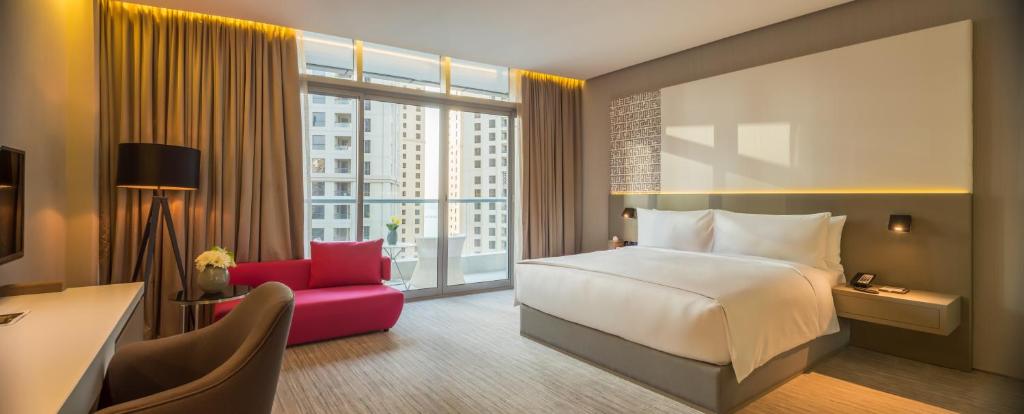 a hotel room with a bed and a red chair at InterContinental Dubai Marina by IHG in Dubai