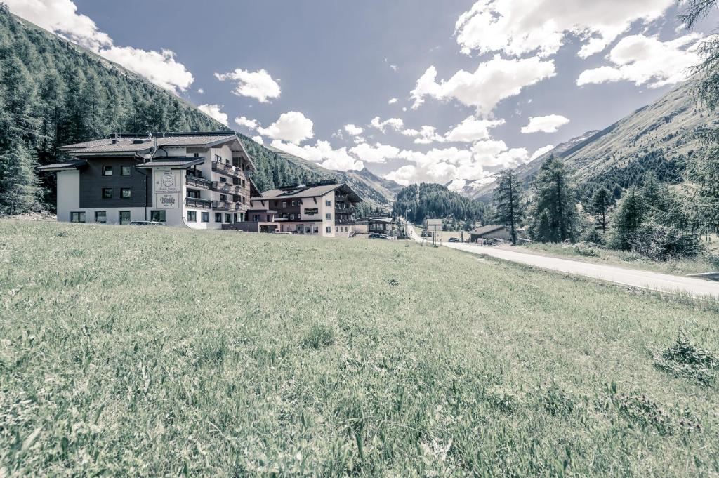 ein Gebäude auf einem Hügel mit einem Grasfeld in der Unterkunft Smarthotel Bergresidenz - Adults only in Obergurgl