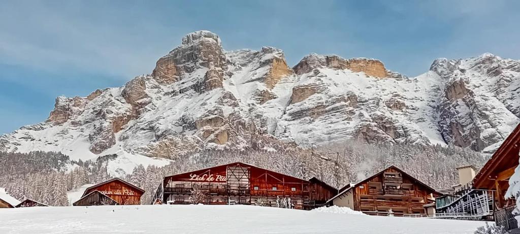 a snow covered mountain in front of a lodge at Lüch Da Pćëi in San Cassiano