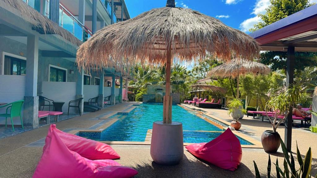 a resort with a pool with pink pillows and an umbrella at Pinky Bungalow Resort - SHA Extra Plus in Ko Lanta