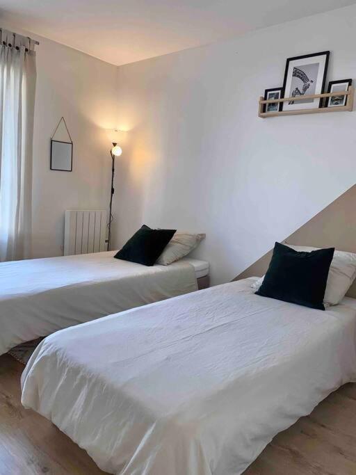 deux lits dans une chambre aux murs blancs dans l'établissement Le Parisien - Bel Appartement à 10mn de Paris, à Suresnes