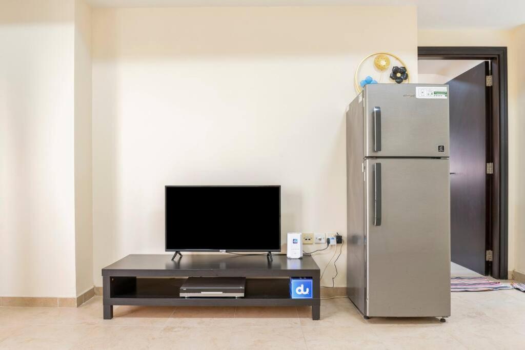 un soggiorno con TV e frigorifero di Beautiful 1BR Apt with city views at silicon Dubai a Dubai