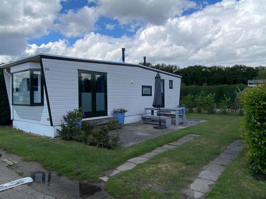 a small white cottage with a bench in a yard at Van Gogh-style chalet near the Loonse and Drunense Duinen in Udenhout