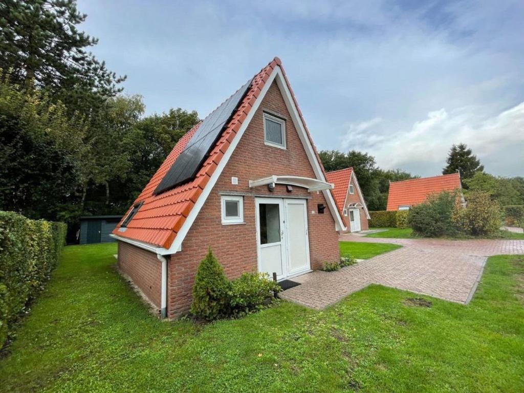 een klein bakstenen huis met een rood dak bij Holiday home Landgoed Eysinga State 4 in Sint Nicolaasga
