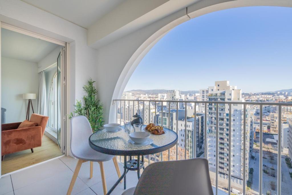 une chambre avec un balcon avec une table et des chaises dans l'établissement La Porte Bleue - Charmant appt, à Marseille