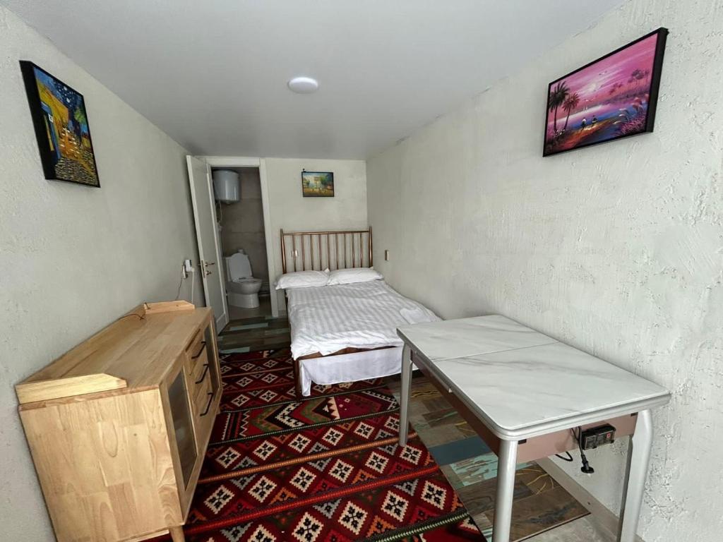 Kleines Zimmer mit einem Bett und einem Tisch in der Unterkunft Гостевой дом «Орман» in Qarqaraly