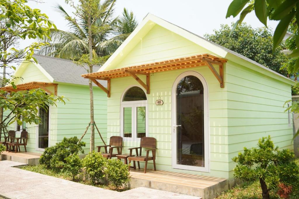 a small green house with chairs on a porch at B&H Villa in Lang Co