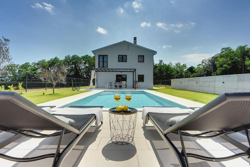 una piscina con 2 copas de vino en un patio en Villa Sain by IstriaLux, en Marčana