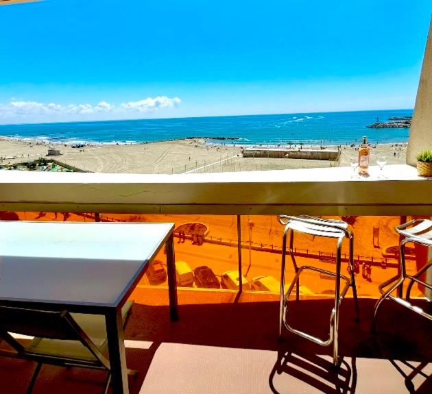 un balcon avec une table et des chaises et une vue sur la plage dans l'établissement Petit nid d’Amour, terrasse, vue mer, 1ère ligne, à Palavas-les-Flots