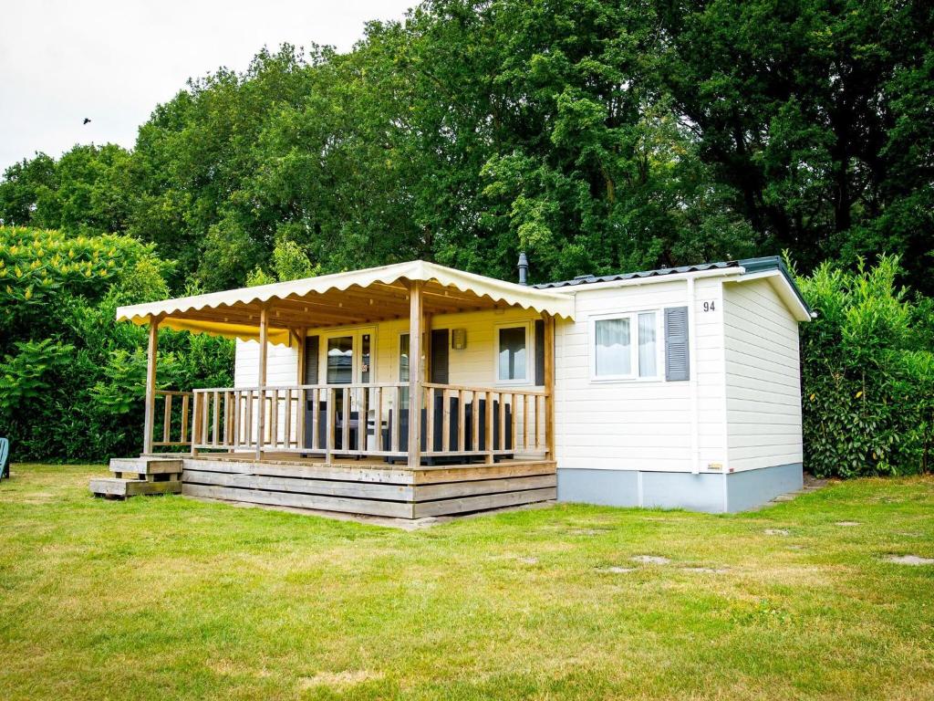 uma pequena casa branca com um alpendre num quintal em Recreatiepark Duinhoeve 4 em Udenhout